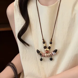 Vue détaillée d'un collier ethnique en perles de bois avec pendentif pois en tissu
