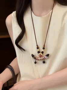Vue détaillée d'un collier ethnique vintage avec perles de bois et pendentif pois