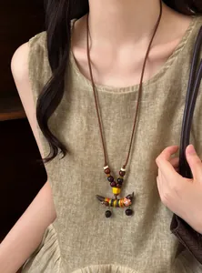 Gros plan d'un collier pendentif pois en bois de style ethnique sur une robe
