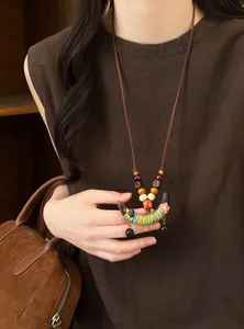 Collier ethnique fait main avec pendentif en bois en forme de cosse de pois colorée.