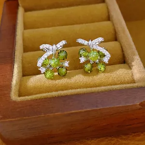 Elegant silver-toned bow earrings with sparkling green floral beads and cubic zirconia
