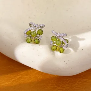 Detailopname van elegante olijfgroene glazen bloem oorknopjes met zirkonia en zilveren naald