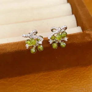 Close-up van elegante zilveren strik oorknopjes met groene gefacetteerde kralen en zirkonia