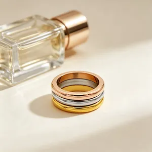 Close-up of three stacked stainless steel rings in gold, silver, and rose gold finishes.