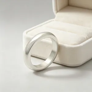 Close-up of polished stainless steel band ring standing by a plush jewelry box.