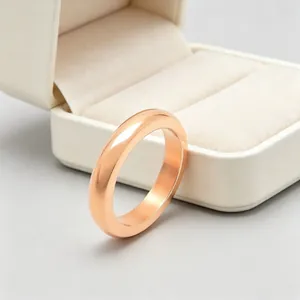Macro view of a polished rose gold stainless steel ring band leaning against a beige box