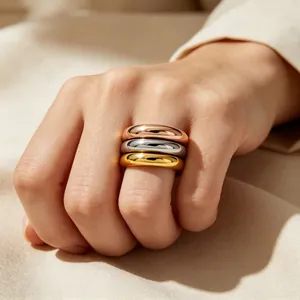 Close-up of three polished gold, silver, and rose gold stackable stainless steel rings