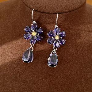 Detailaufnahme von Vintage-Ohrringen mit lila Zirkonia-Blume und Wassertropfen