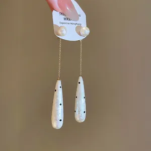 Detail shot of French vintage water drop pearl earrings with chic black polka dots
