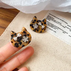 Close-up of leopard pattern cat stud earrings with heart bow and flower rhinestones