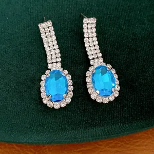 Nahaufnahme eleganter blauer Edelstein-Ohrhänger mit funkelndem Strass-Halo-Detail