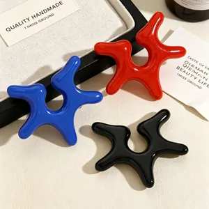 Detailed macro view of niche irregular star-shaped acrylic ear clips in blue, red, and black