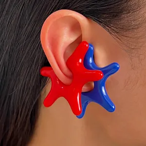 Macro detail shot of vibrant red and blue acrylic starfish-shaped ear cuffs on an ear