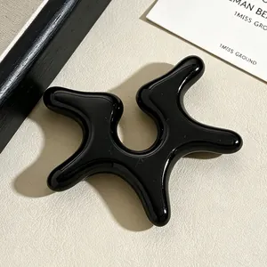 Detailed close-up of a glossy black irregular starfish-shaped acrylic non-piercing ear cuff