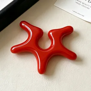 Macro detail of red irregular starfish acrylic ear clip with vibrant glossy finish