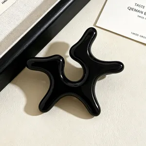 Close-up of black irregular starfish-shaped acrylic ear cuff for non-pierced ears