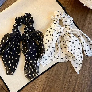 Close-up view of chic fabric polka dot bow scrunchies displayed on a texture board.
