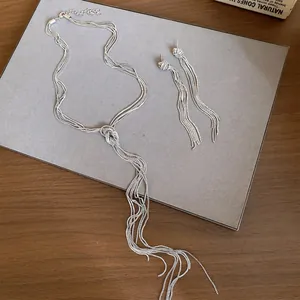 Gedetailleerd overzicht van geknoopte ketting met kwastjes en bijpassende zilveren oorbellen.