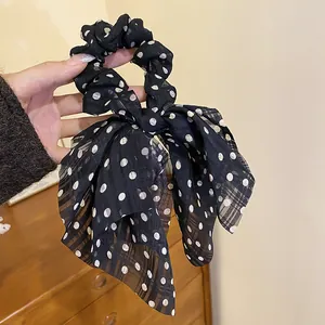 Detail view of black polka dot bow scrunchie showing sheer fabric texture