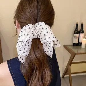 Detailed back view of a fashion model wearing a white polka dot bow hair scrunchie.