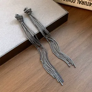 Detailopname van gunmetal grijze geknoopte kwastjes oorbellen op houten ondergrond