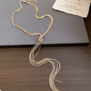 Gedetailleerd beeld van de gouden geknoopte ketting met meerstrengs kwastjes op een bord.