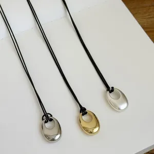 Minimalistische Halskette mit elliptischem Anhänger und schwarzem Lederband in Gold und Silber