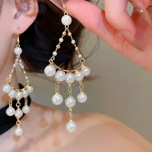 Gros plan de boucles d'oreilles pendantes dorées de style vintage avec plusieurs perles.