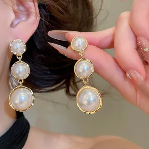 Vue détaillée de boucles d'oreilles vintage à trois perles avec finition dorée élégante