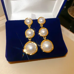 Gros plan de boucles d'oreilles pendantes à trois perles de style cour française