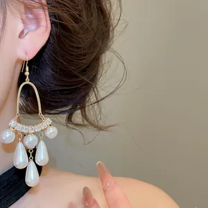 Boucles d'oreilles de style palais français avec pampilles de perles portées par un modèle