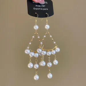 Détail de boucles d'oreilles en perles style palais français avec des pompons dorés