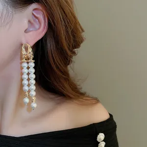 Gros plan détaillé de boucles d'oreilles élégantes à pompons en perles blanches doubles