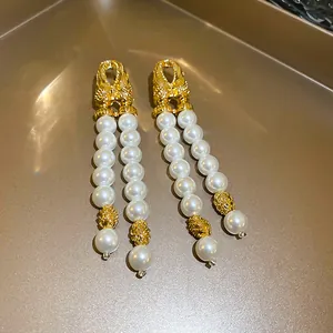 Gros plan sur d'élégantes boucles d'oreilles à double pampille de perles dorées.