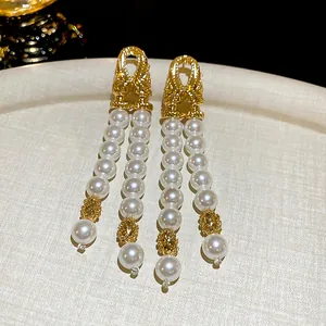 Gros plan d'élégantes boucles d'oreilles à pampilles en perles à double couche dorées.