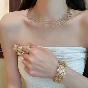 Close-up of gold multi-layer choker, cuff bracelet and rings set worn by a model