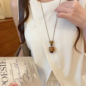 Detailweergave van een handgesneden houten berenhanger aan een lange bruine koordketting