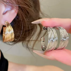 Close-up detail of multi-layer textured metal hoop earrings in gold and silver finishes