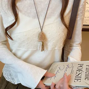 Detailopname van een retro houten vis hanger ketting met kralen kwastjes op een model