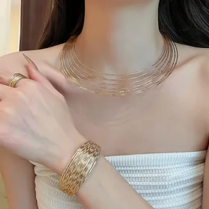 Close-up of elegant gold multi-layered choker, wide cuff bracelet and ring set for women.
