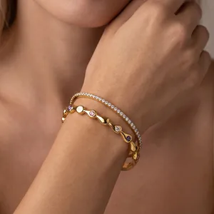 Elegantes Detail zweier 18k vergoldeter Edelstahlarmbänder mit lebhaften farbigen Kristallen