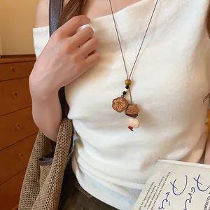 Gedetailleerde close-up van een vintage houten beren hanger ketting op een witte top.