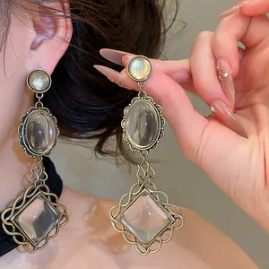 Detailed macro view of vintage oval lace drop earrings with clear resin stones in gold tone