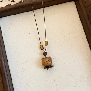 Detailopname van een schattige handgemaakte houten beerhanger aan een vintage ketting.