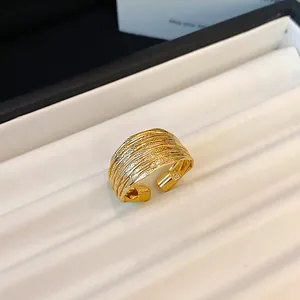 Close-up detail of a wide gold-colored ring featuring a multi-layer textured wire design