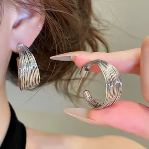 Close-up of silver-tone multi-layer hoop earrings showing fine textured finish and stud closure