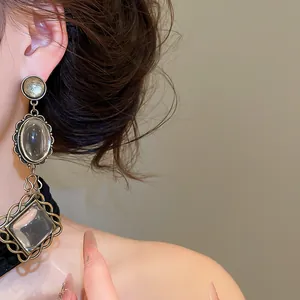 Close-up of vintage oval lace drop earrings with clear crystals on ear