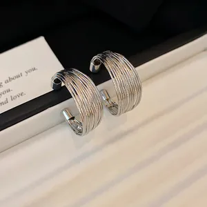 Close-up of silver-colored metal multi-layer hoop earrings with textured wire design