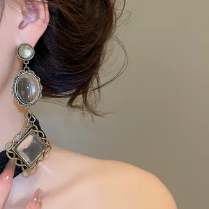 Macro shot of vintage style earrings with ornate metal frame and clear stones on ear.