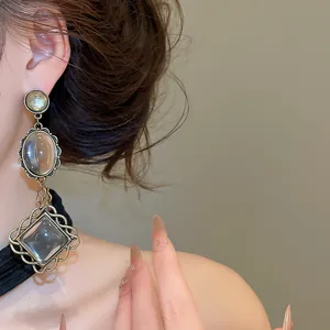 Detail view of vintage-style drop earrings featuring oval and geometric resin pendants.